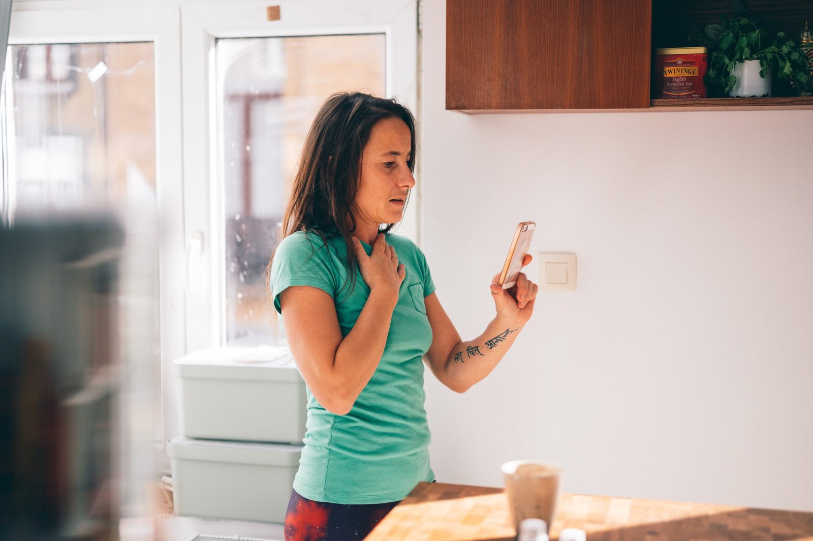 woman in green shirt holding smartphone